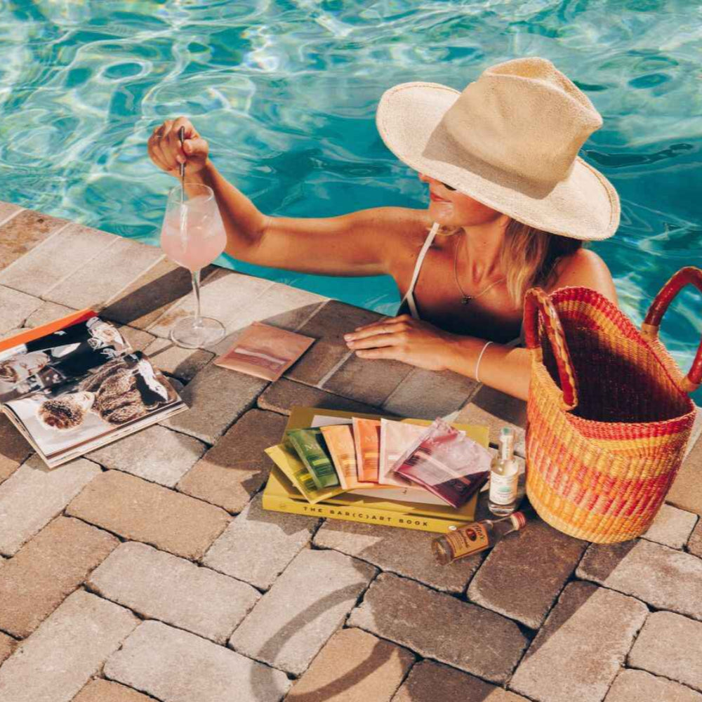 
                  
                    Person by a poolside with a hat, magazine, and bag drinking a Mixxer
                  
                